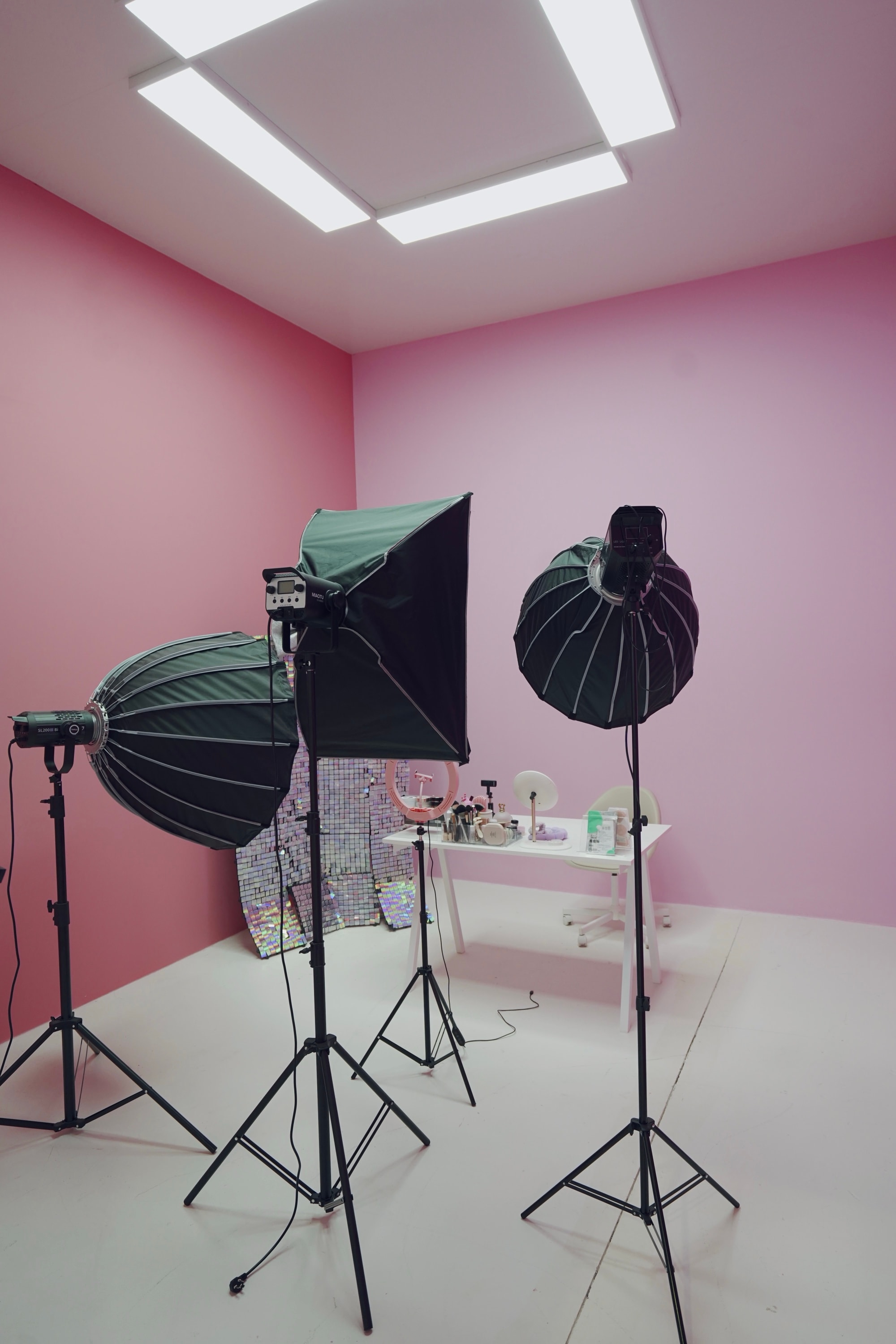 Pink beauty live-streaming room at PROFECIABRAND — a vanity of cosmetics and ring light against a sequinned backdrop