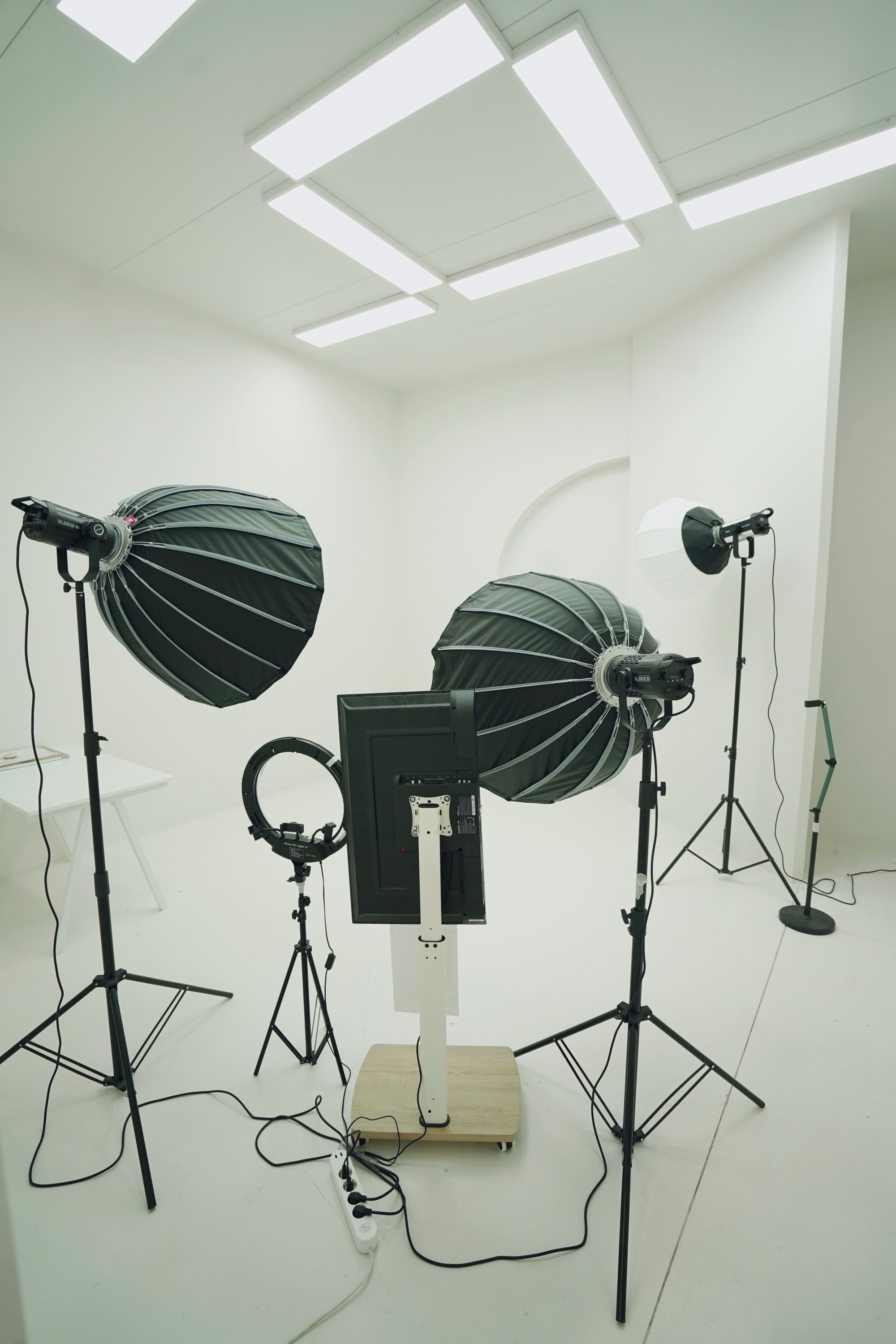 White live-streaming room at PROFECIABRAND — softbox lighting, ring light and a broadcast monitor set for a live session