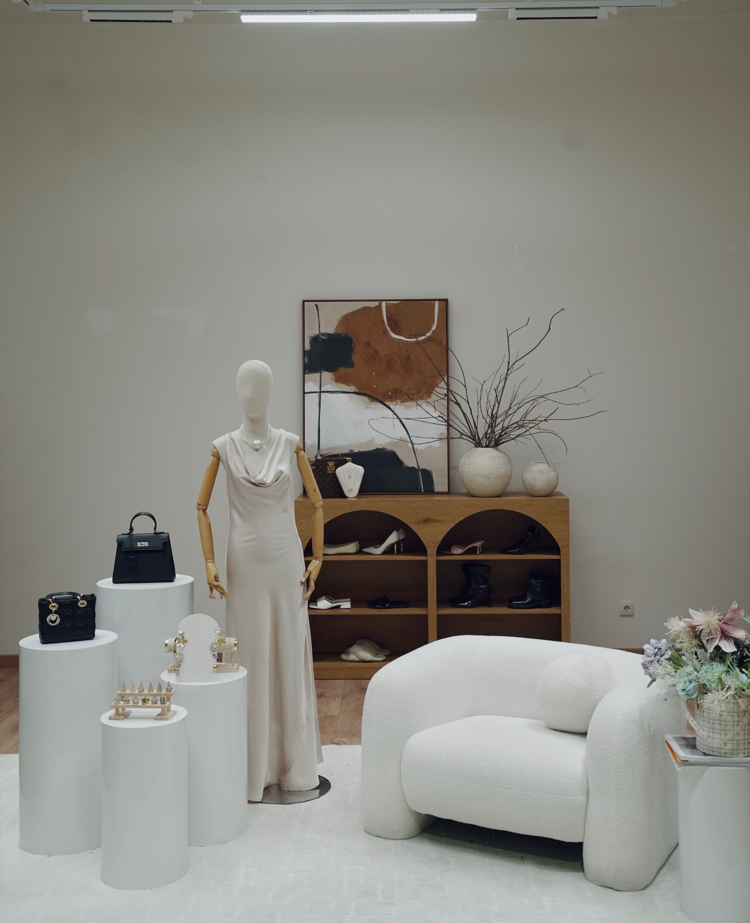 Product styling set at PROFECIABRAND — a mannequin in a cream gown with handbags and jewellery staged on plinths