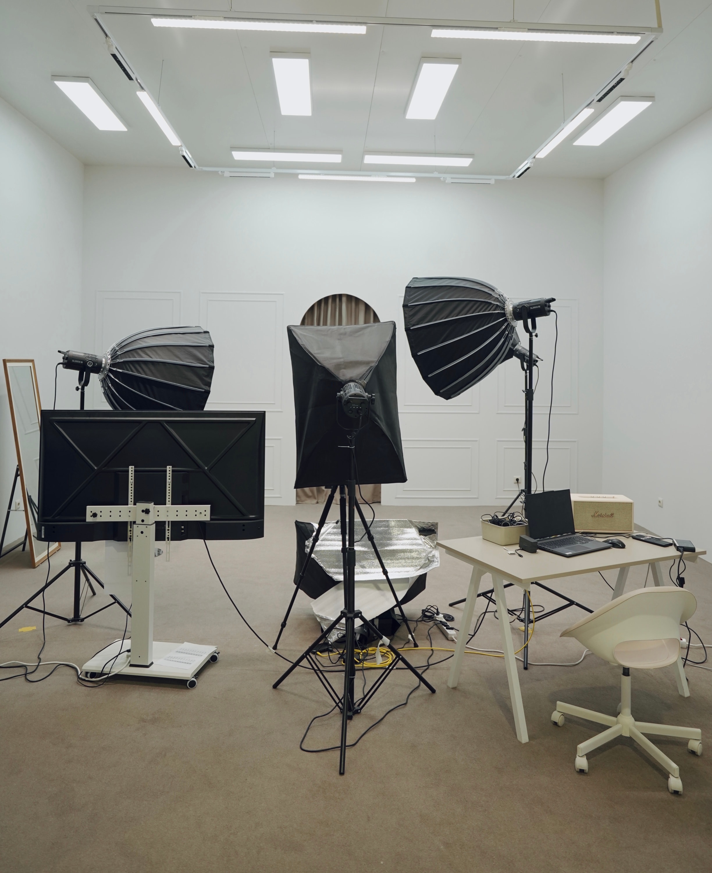 PROFECIABRAND production studio — softboxes, a broadcast monitor and an editing desk in an arched-alcove set