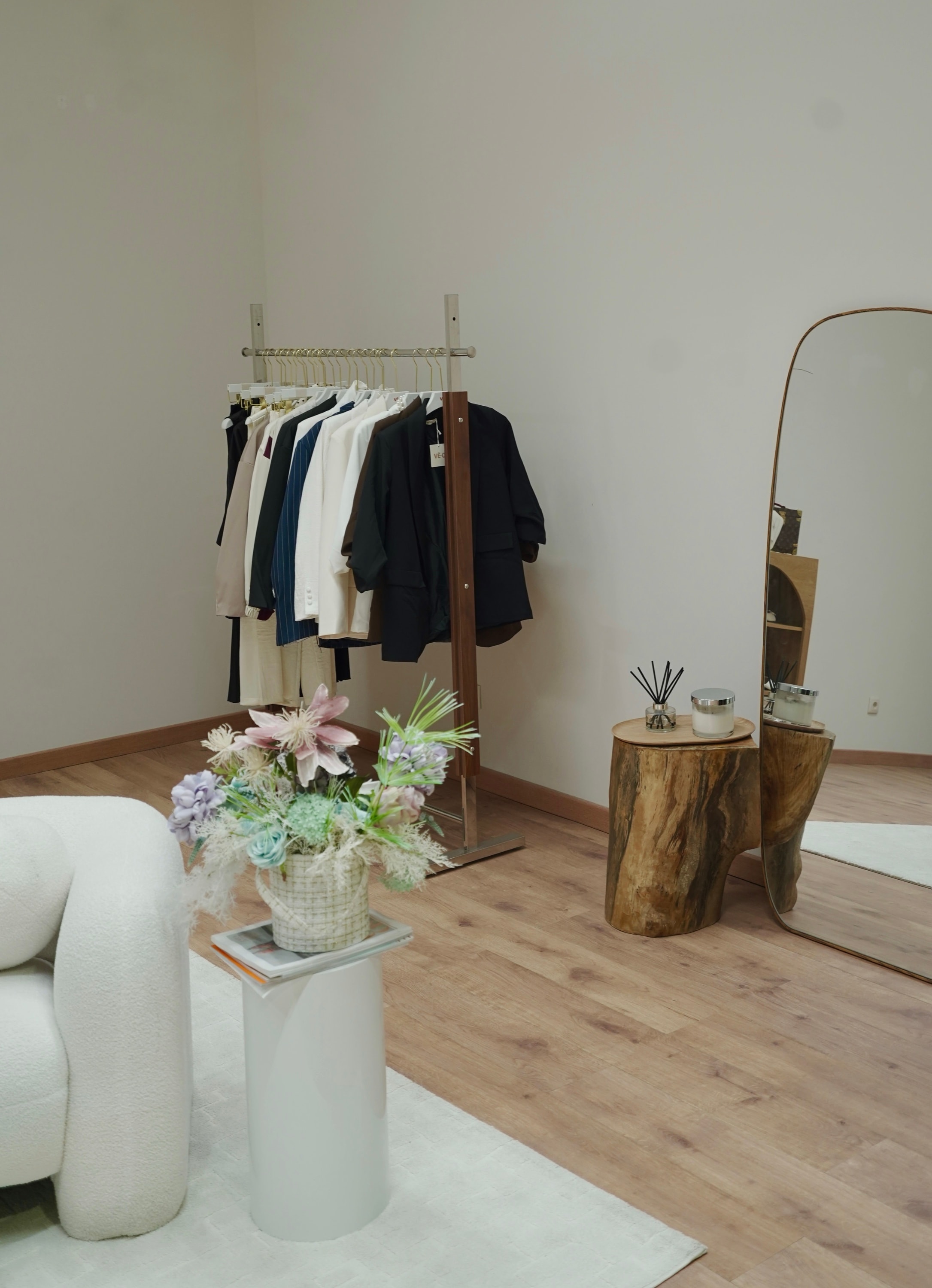 VÊ-O styling corner — a neutral-toned garment rail, full-length mirror and dried florals beside a bouclé chair