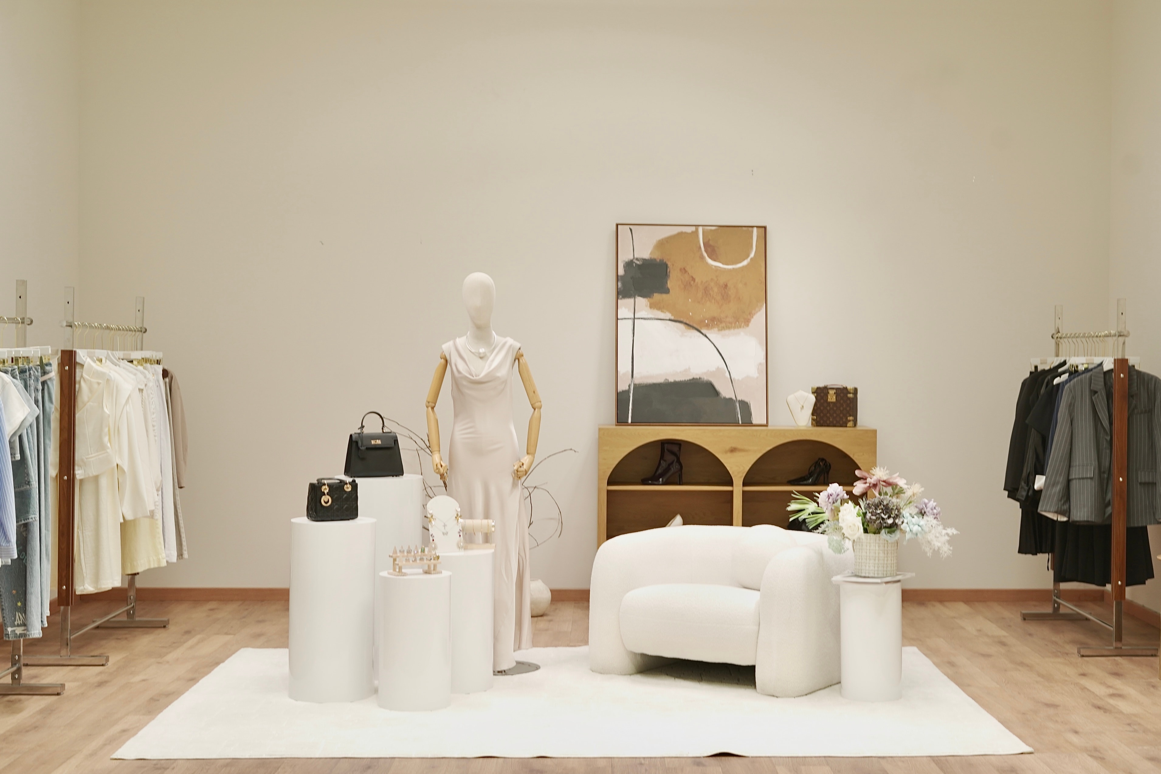 PROFECIABRAND studio set — cream-on-cream interior with mannequin, wood furniture, and abstract art